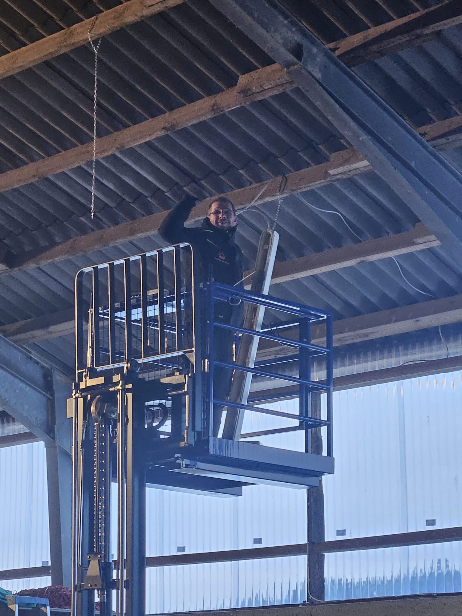 Ein Mann steht in einer Lagerhalle auf einem Gabelstapler.