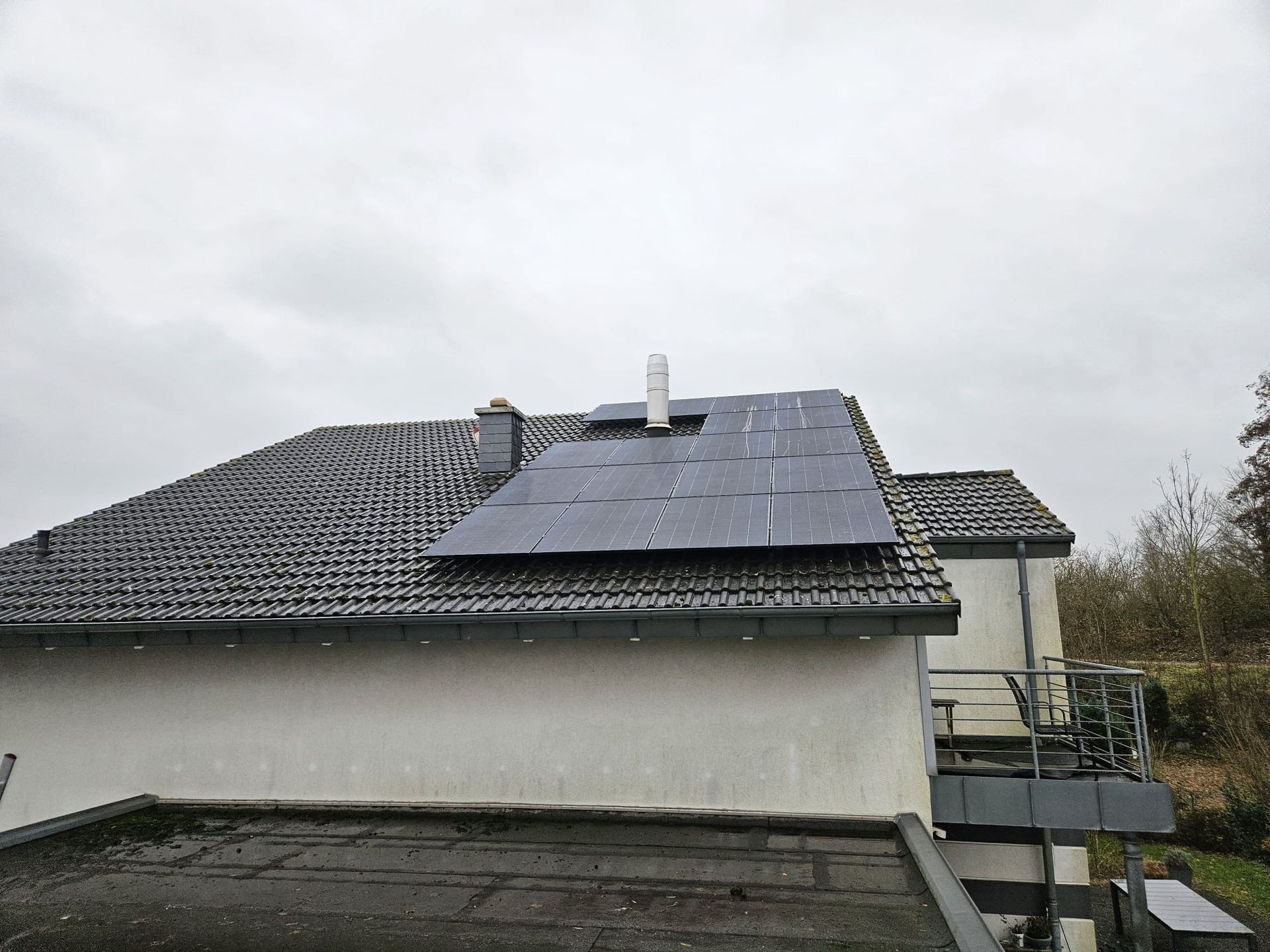 Ein Haus mit Sonnenkollektoren auf dem Dach und einem Balkon.