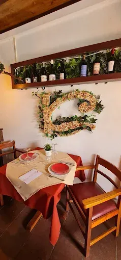 Mesa de restaurante para dos con platos rojos, una pequeña planta y una gran letra