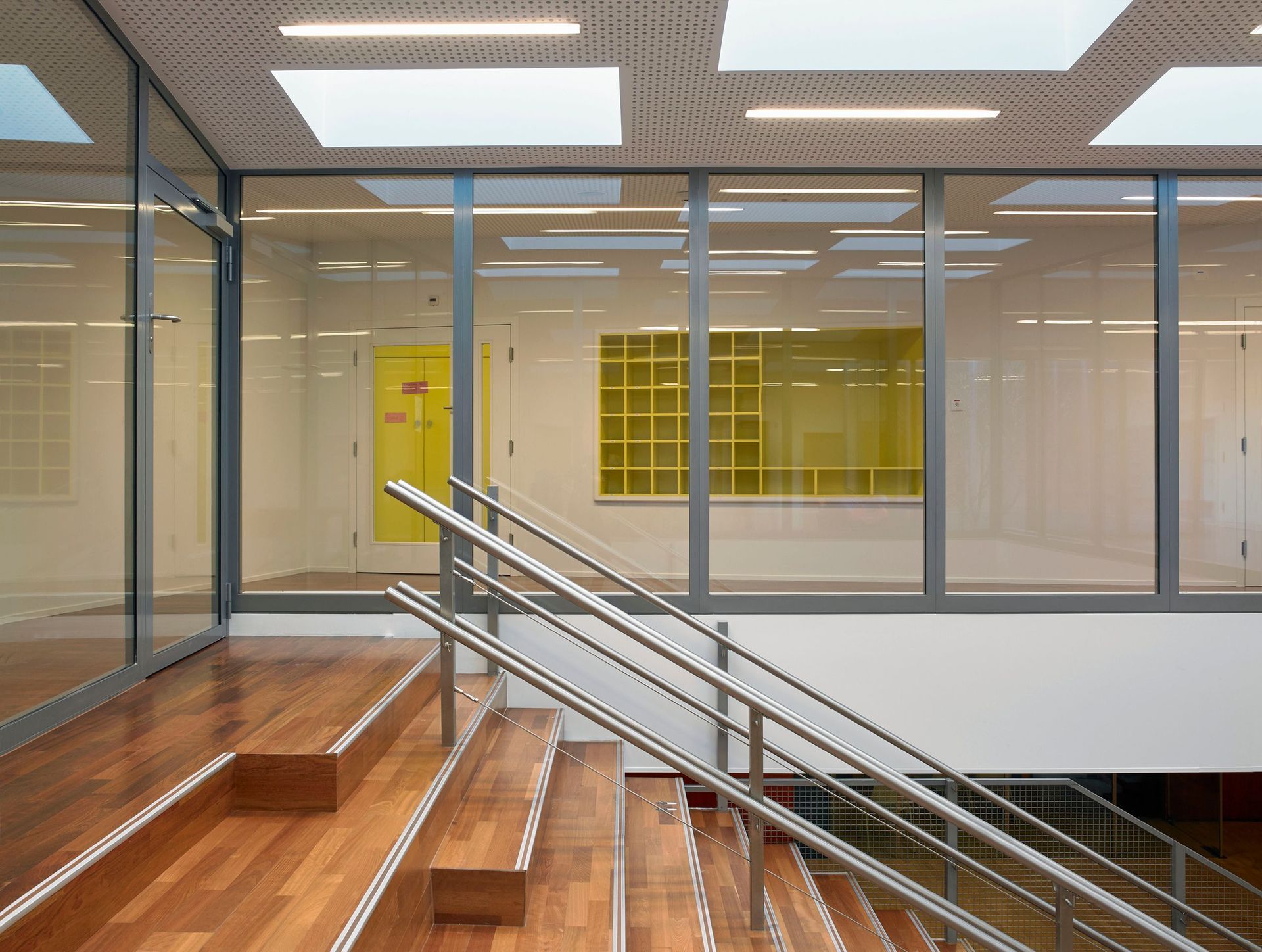 Un escalier dans un immeuble avec des marches en bois et une rampe en acier inoxydable.
