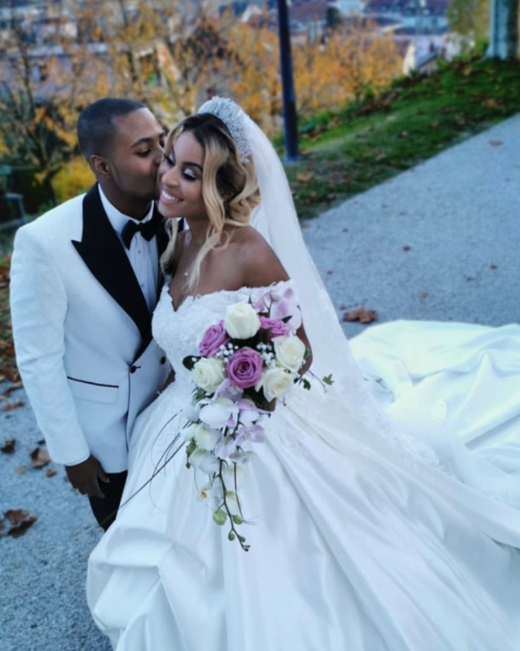 Personne préparant la table avec une nappe blanche, des assiettes bordées d'or et des couverts.