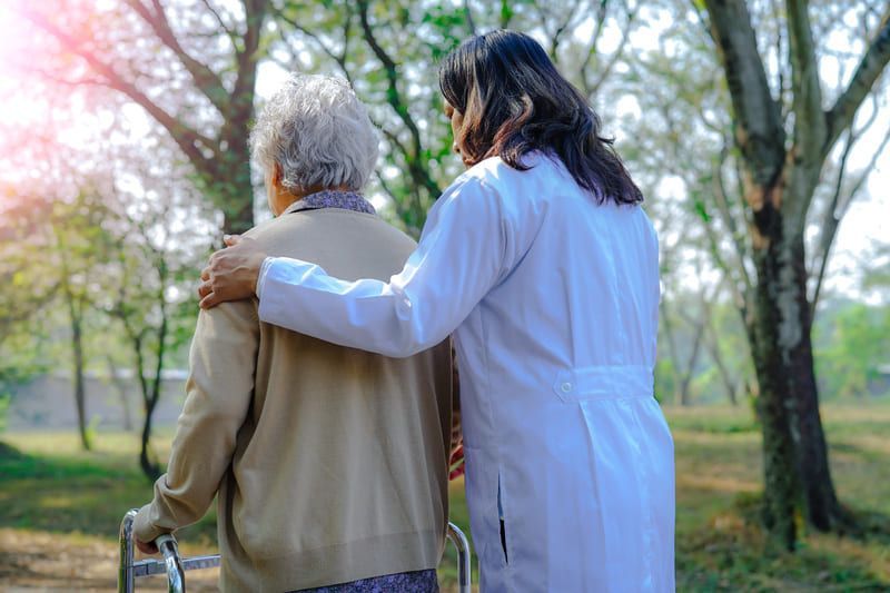 Ein Arzt hilft einer älteren Frau mit einem Walker im Park | St. Brigida Seniorenzentrum