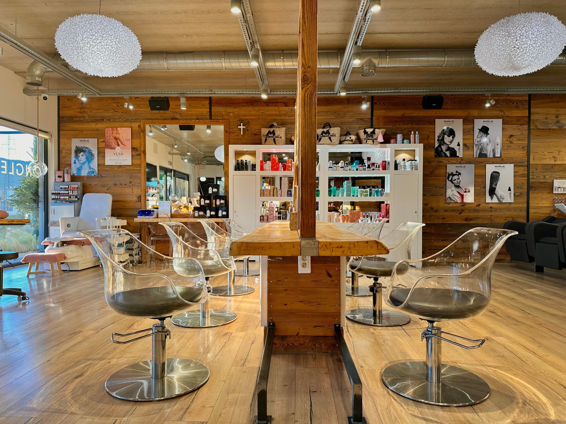 Intérieur de salon moderne avec parquet, mur de miroirs, chaises transparentes et étagères à produits