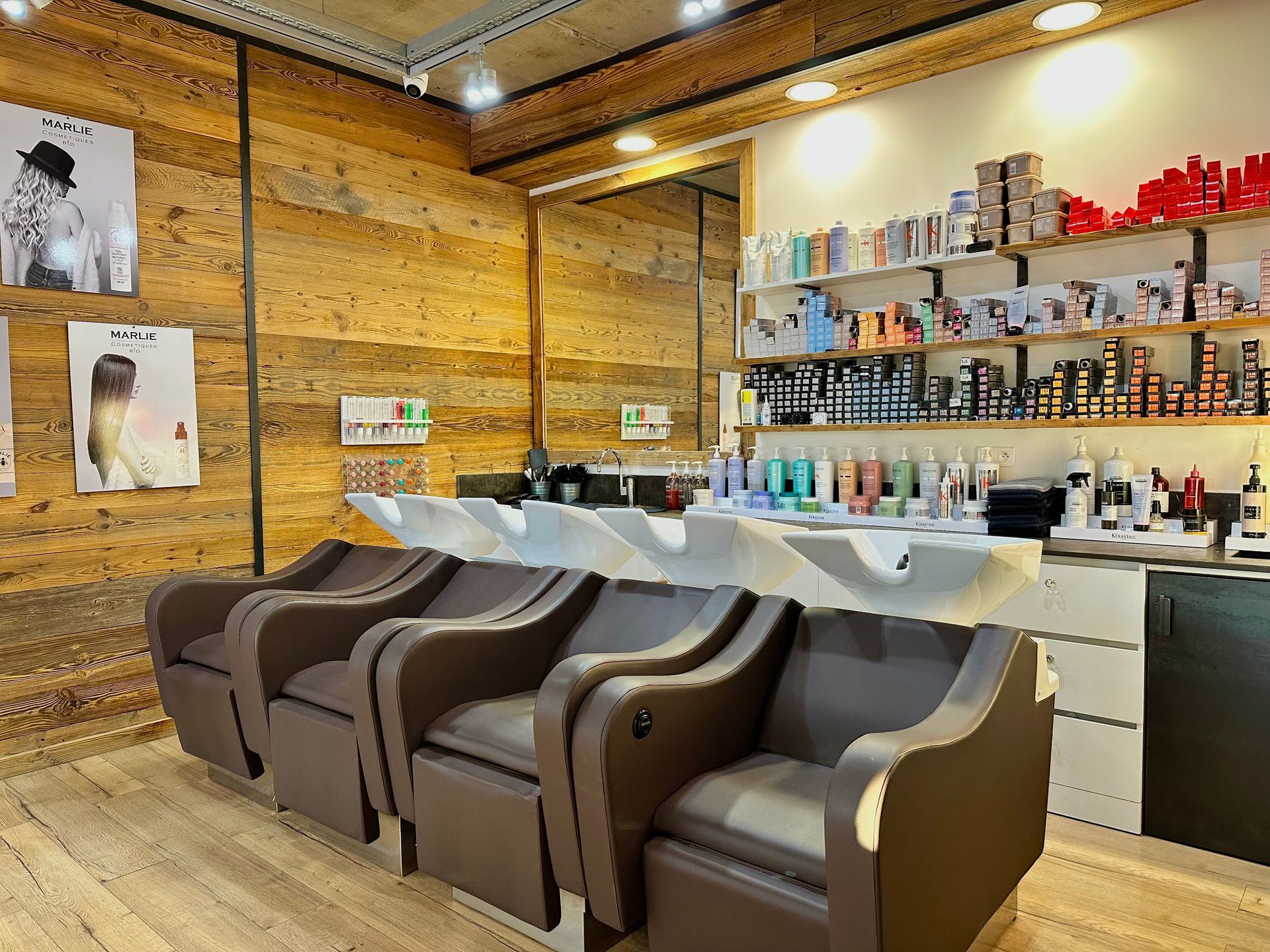 Fauteuils avec lavabos pour le shampoing dans un intérieur lambrissé avec étagères à produits et postes de coiffage