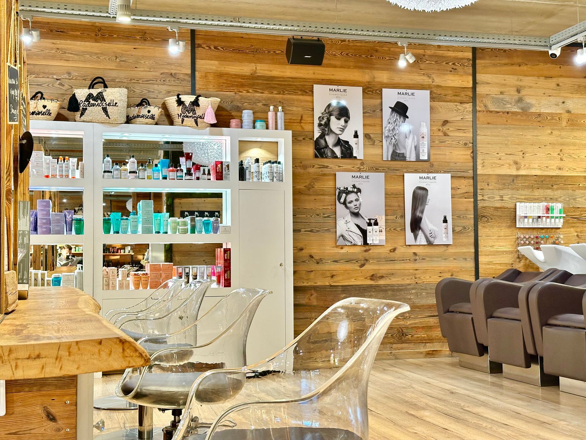 Intérieur de salon de coiffure cosy avec murs en bois, étagères de produits, chaises transparentes et portraits