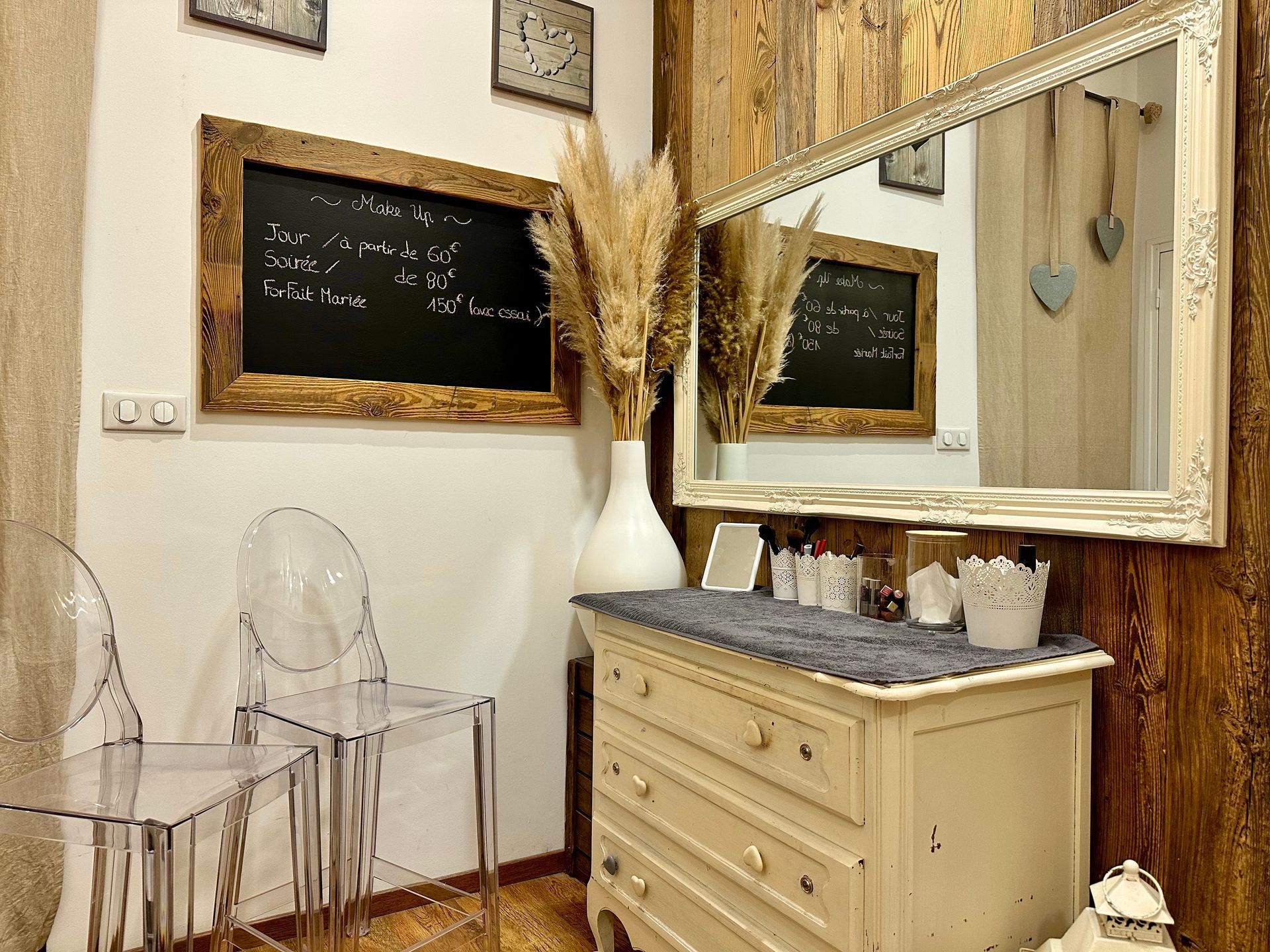 Élégante coiffeuse couleur crème, avec miroir encadré, tableaux noirs et chaises transparentes