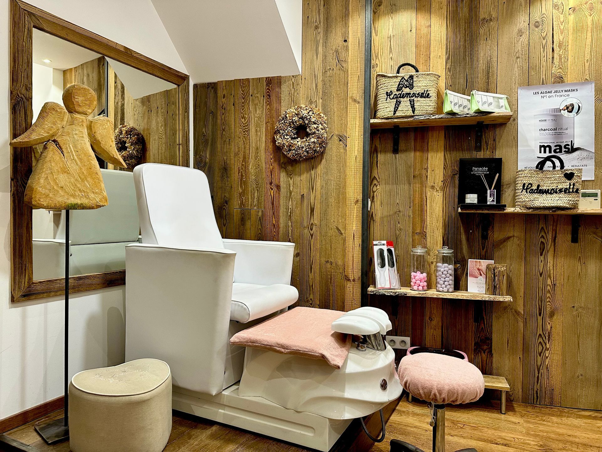 Intérieur de salon de beauté avec fauteuil blanc, murs lambrissés, étagères et touches de rose.