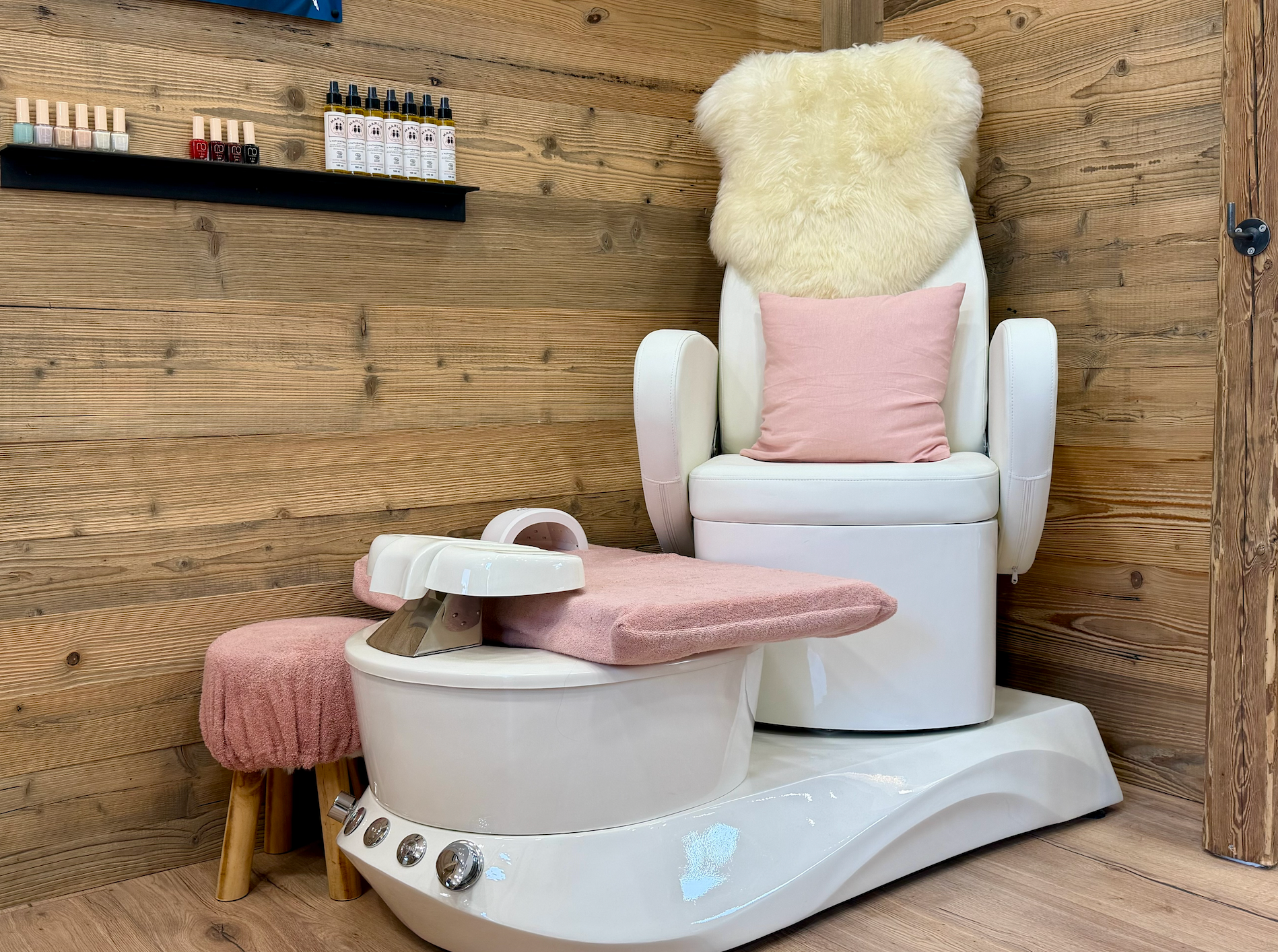 Fauteuil de pédicure blanc avec accessoires roses dans une salle de salon lambrissée