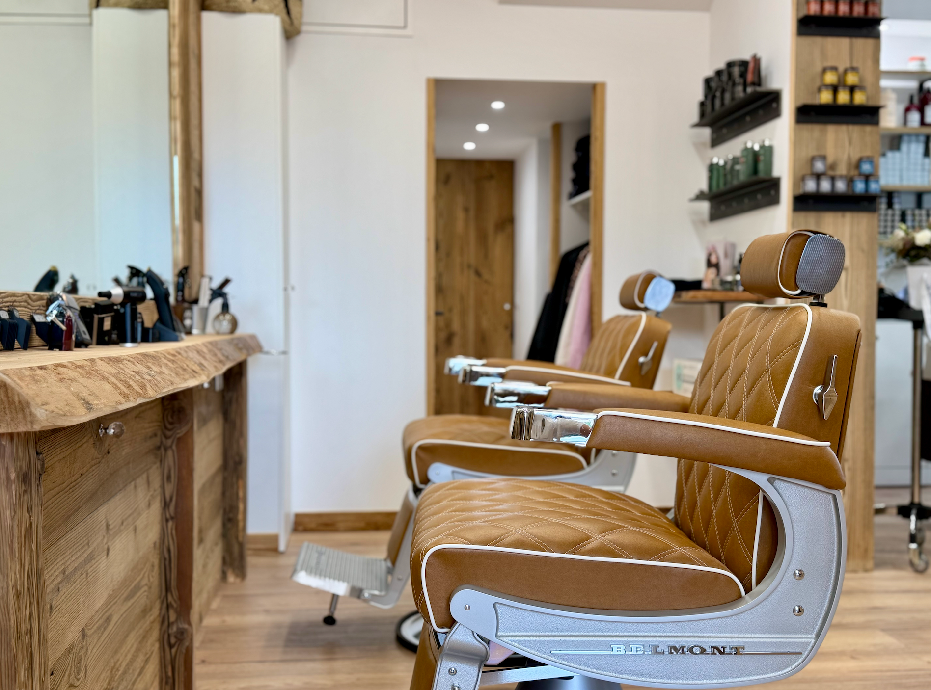 Salon de coiffure vide avec fauteuils en cuir beige et miroirs le long d'un comptoir en bois poli