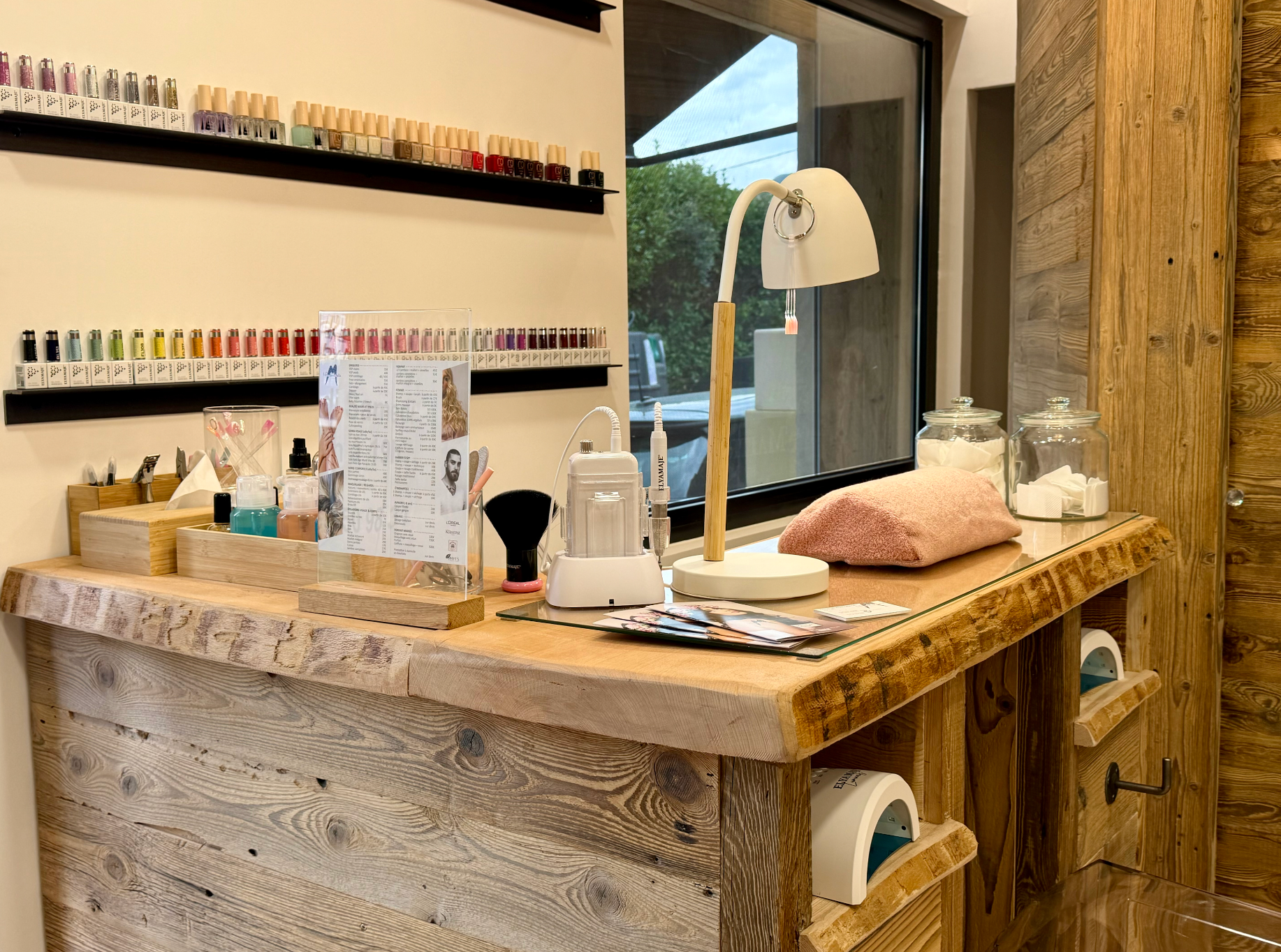 Espace manucure confortable avec présentoirs à vernis, outils de manucure, lampe et repose mains rembourré