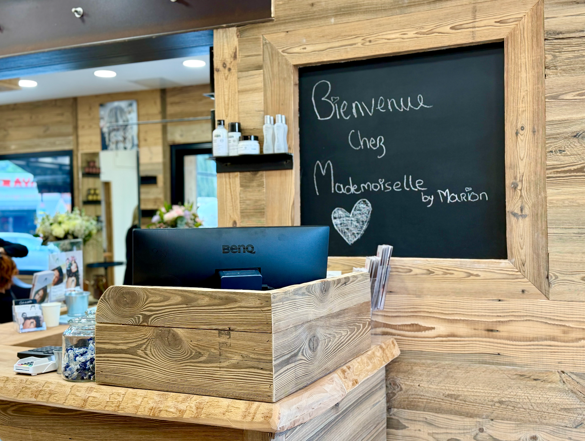 Comptoir avec une ardoise indiquant « Bienvenue chez Mademoiselle by Marion » 