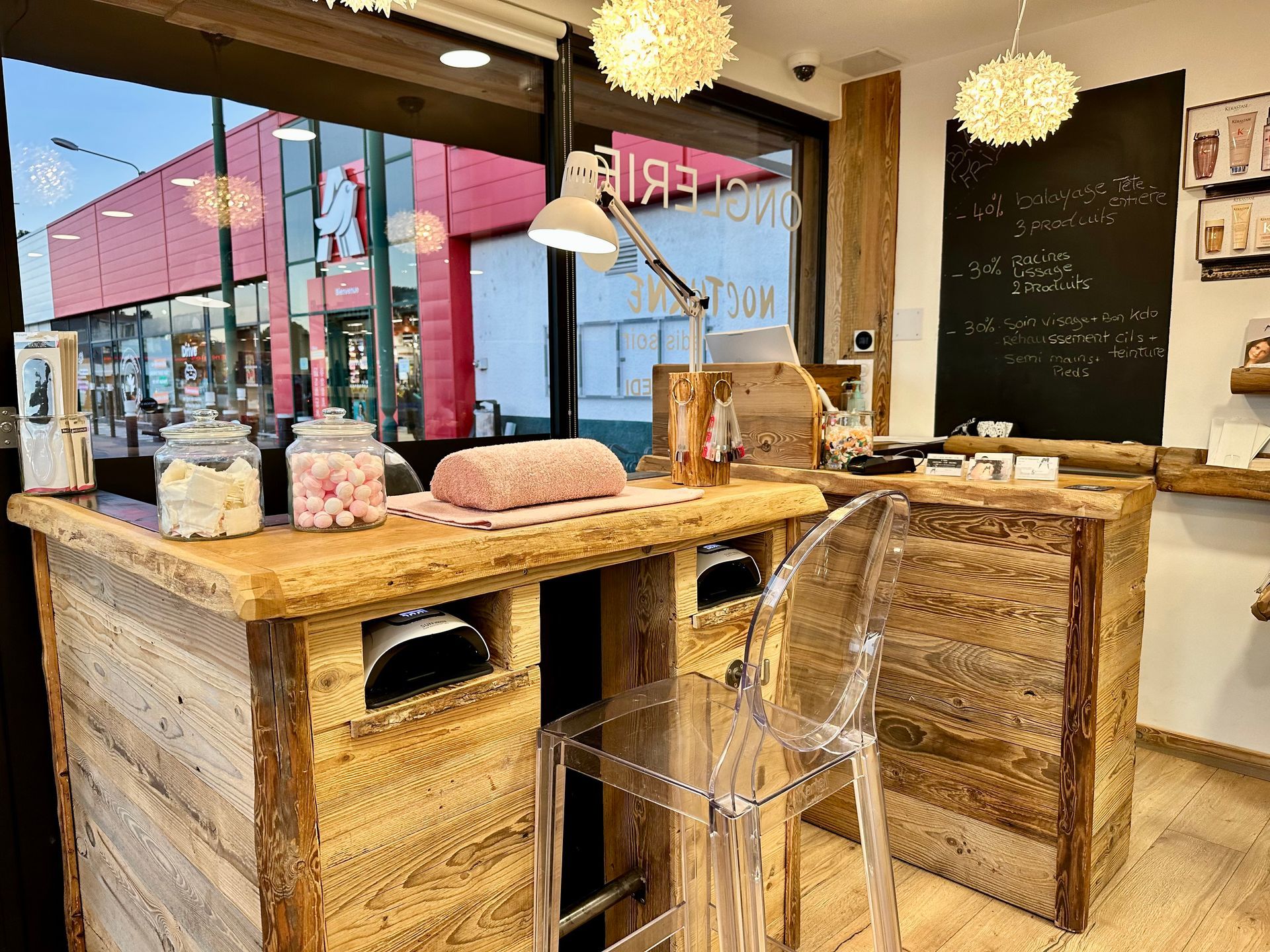 Intérieur cosy avec tables en bois, chaises transparentes et suspensions lumineuses.