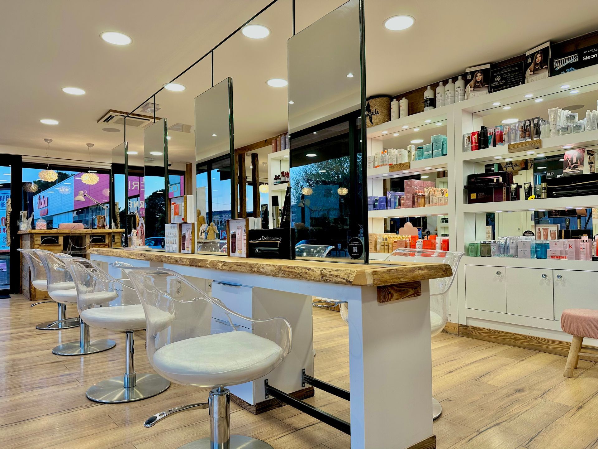 Intérieur moderne d'un salon de coiffure avec fauteuils blancs, postes de travail avec miroirs et étagères de produits