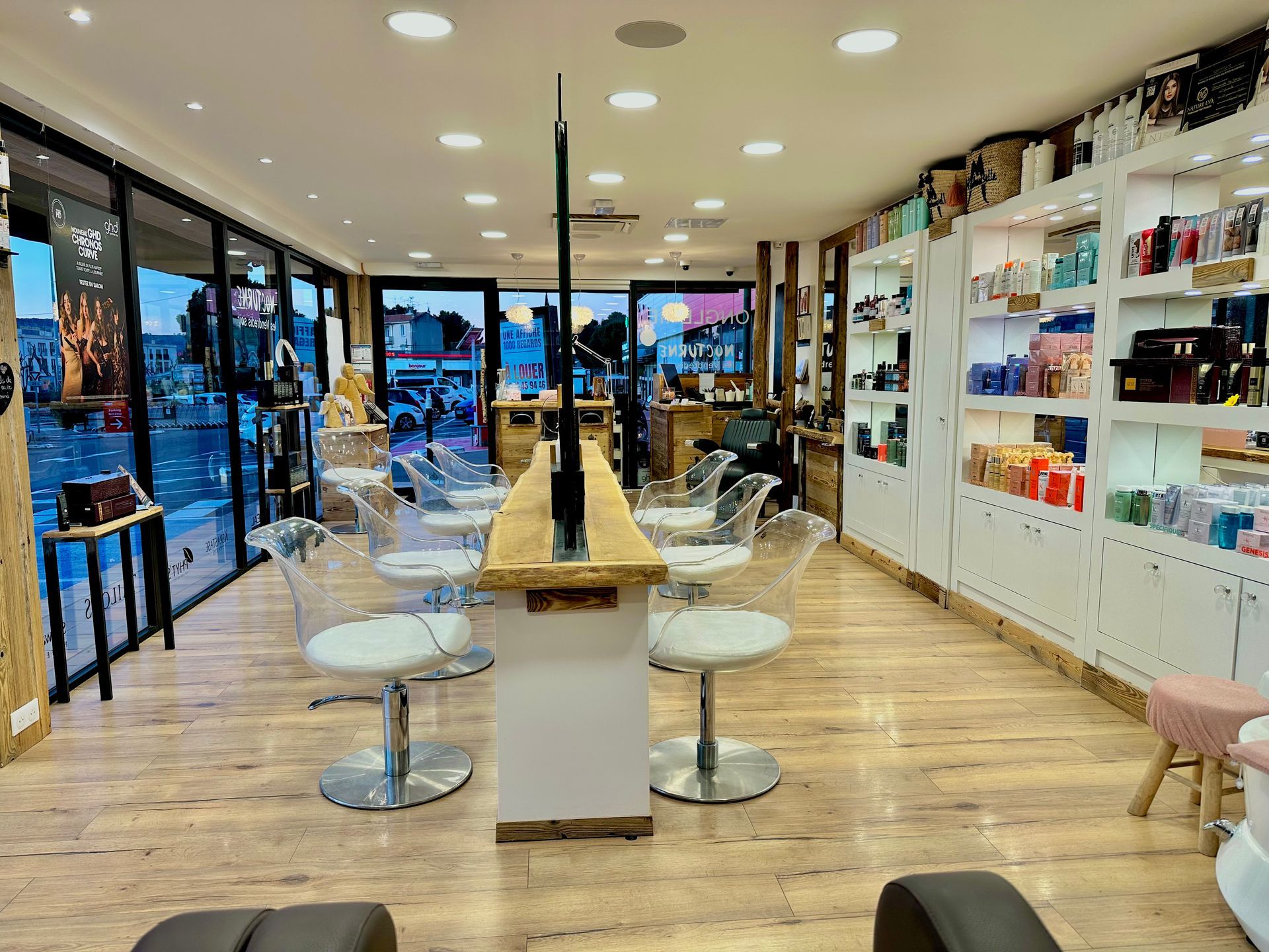 Intérieur lumineux et moderne d'un salon de coiffure avec fauteuils de coiffure, miroirs, étagères et comptoir central.