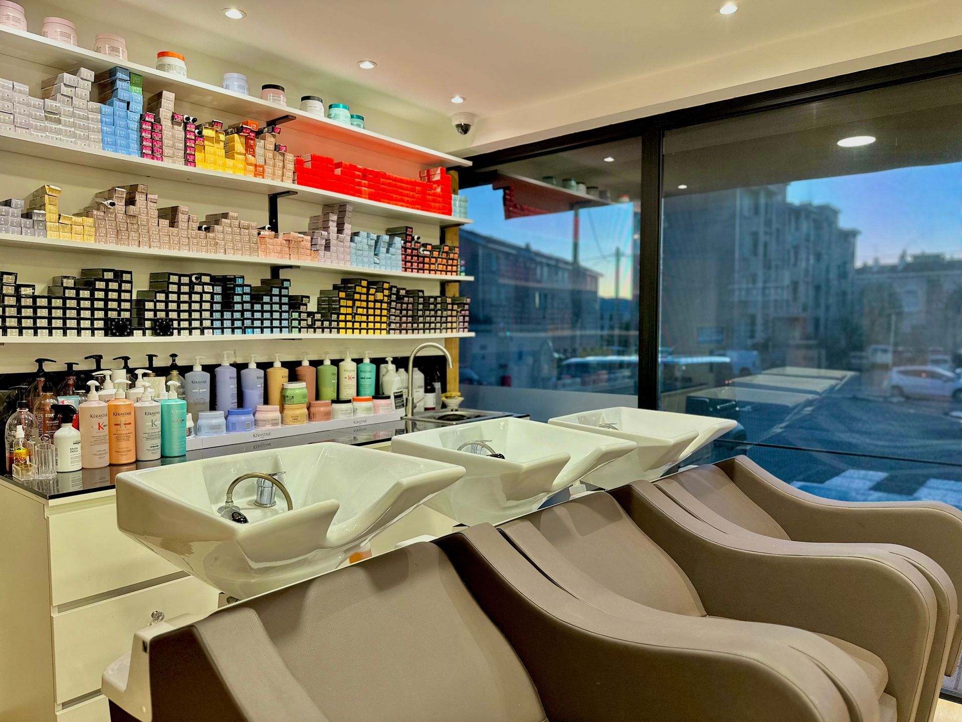 Salon de coiffure moderne avec bacs à shampoing, étagères à produits et grandes fenêtres