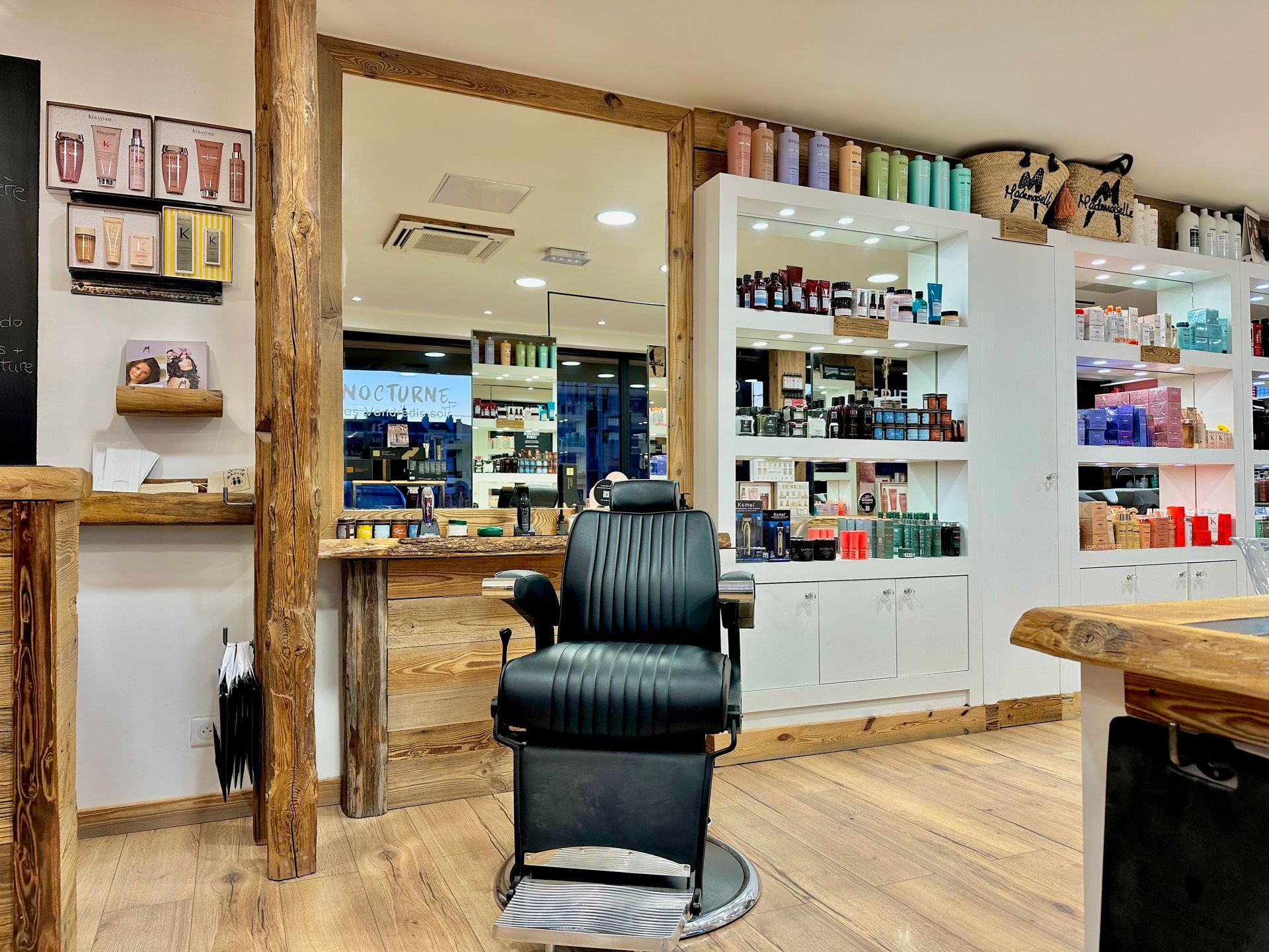 Intérieur d'un salon de coiffure avec un fauteuil de barbier noir, des miroirs et des étagères de produits capillaires
