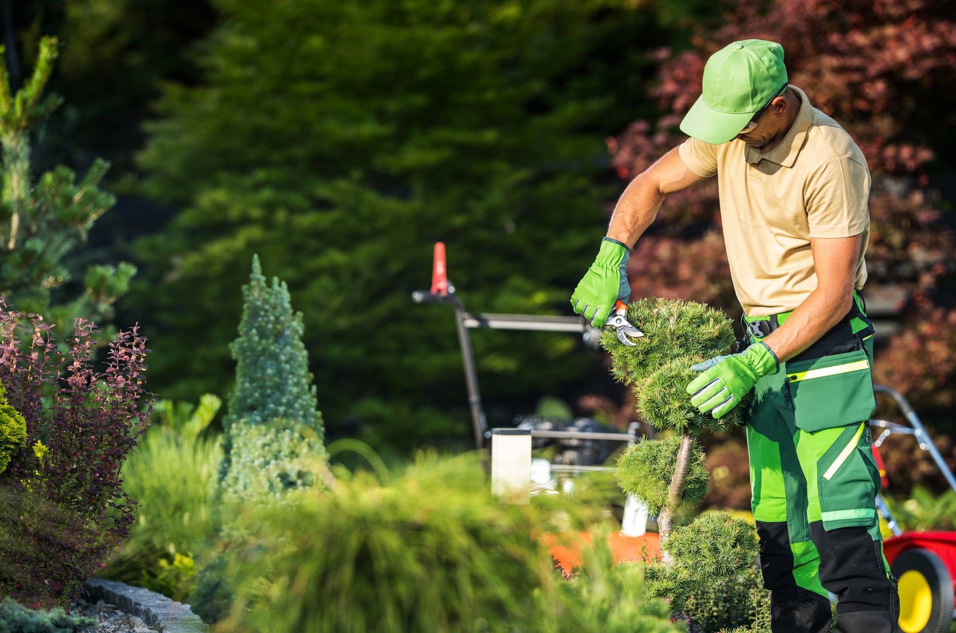 Jardinier en uniforme vert taillant des arbustes dans un jardin ensoleillé