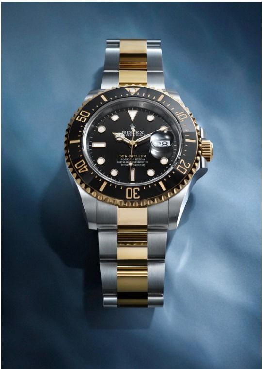 Un reloj Rolex de plata y oro sobre un fondo azul.