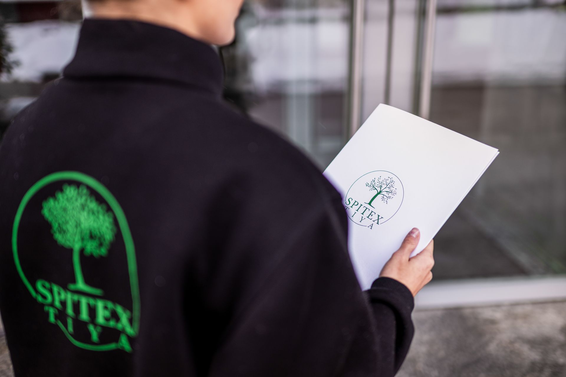 Eine Person, die eine schwarze Jacke mit dem Wort Sptex auf dem Rücken trägt