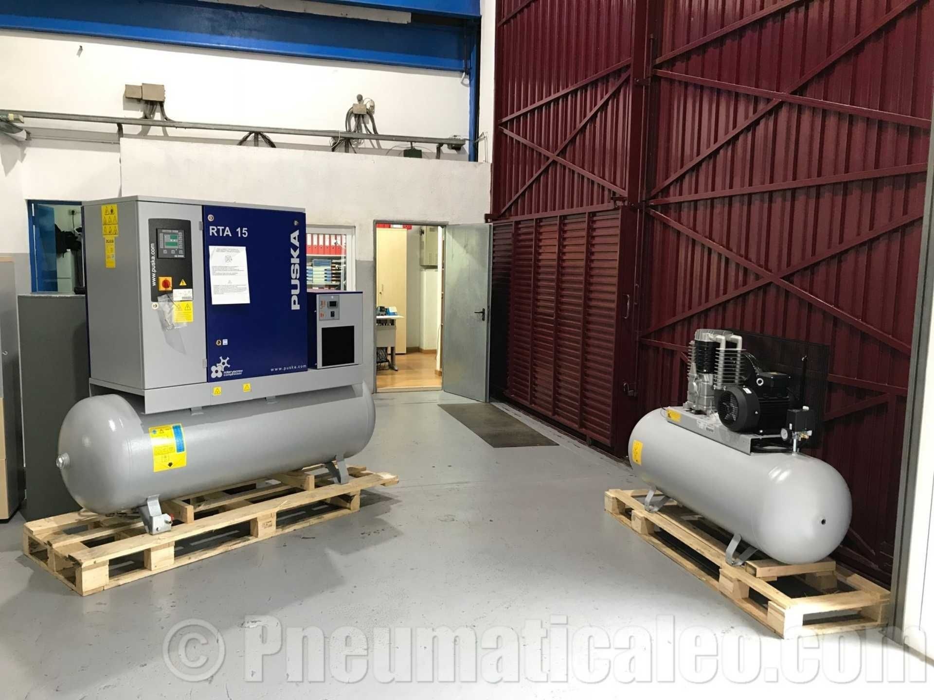 Dos compresores de aire están sobre paletas de madera en un almacén.
