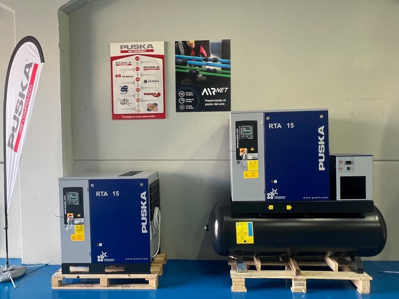 Dos compresores de aire están sobre paletas de madera en una habitación.