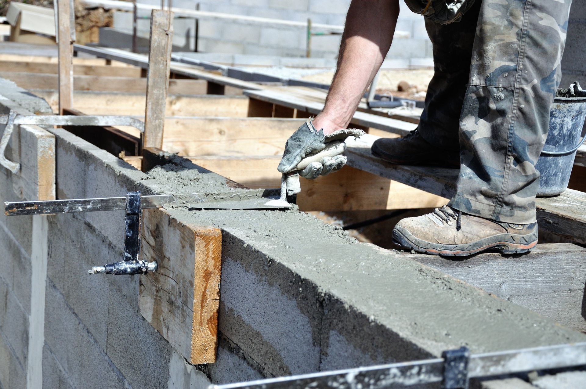 Un ouvrier du bâtiment lisse du béton sur un mur à l'aide d'une truelle.