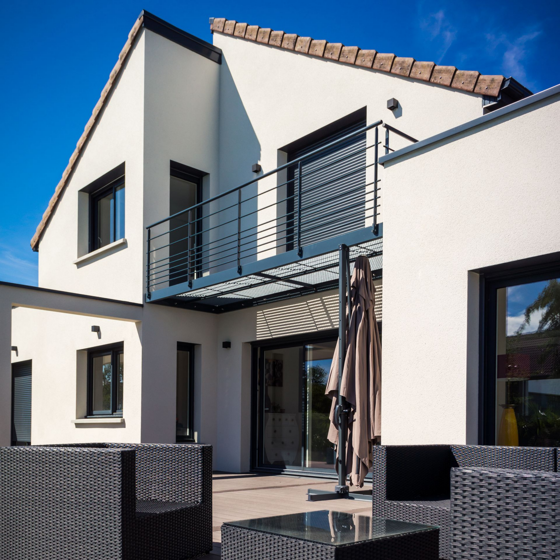 Façade d'une maison moderne avec des fenêtres et un balcon.