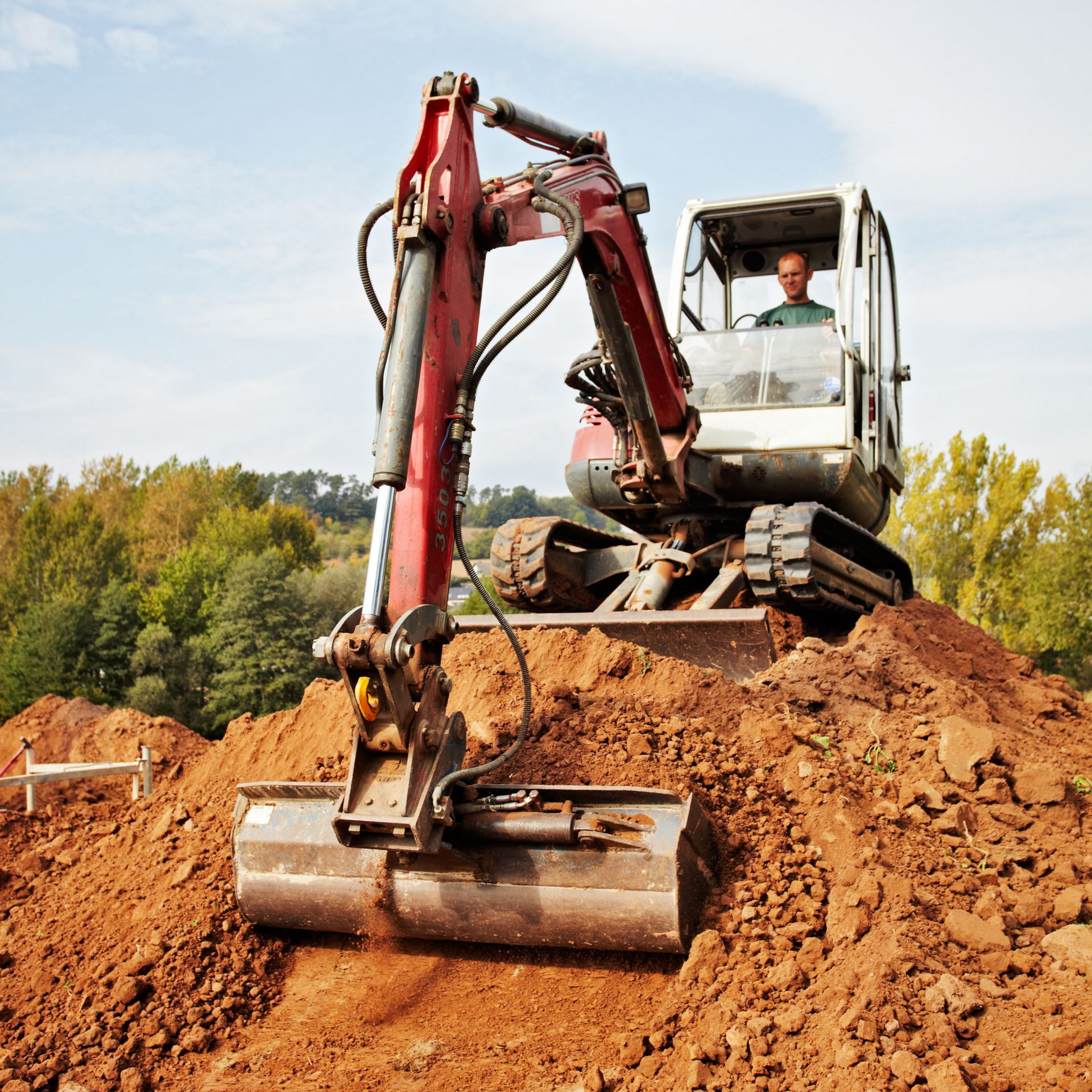 Un terrassier qui manipule une tractopelle pour récupérer de la terre.