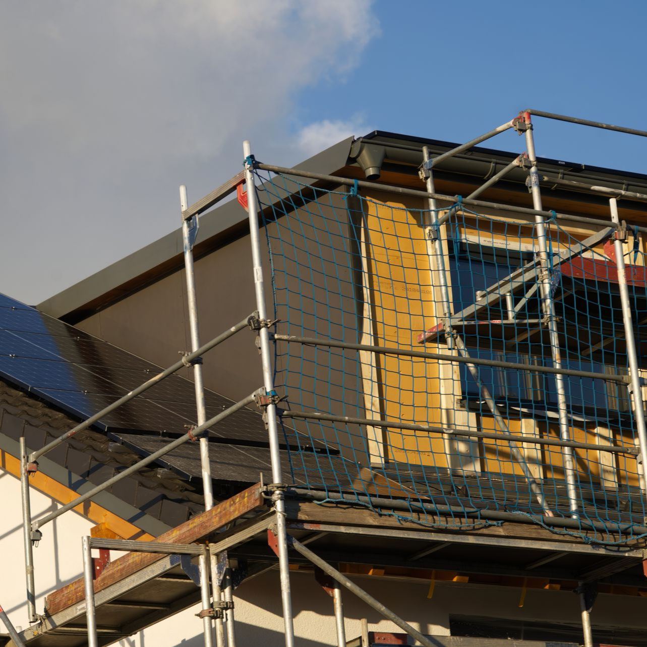 Des échafaudages entourent un bâtiment en train d'être surélevé.