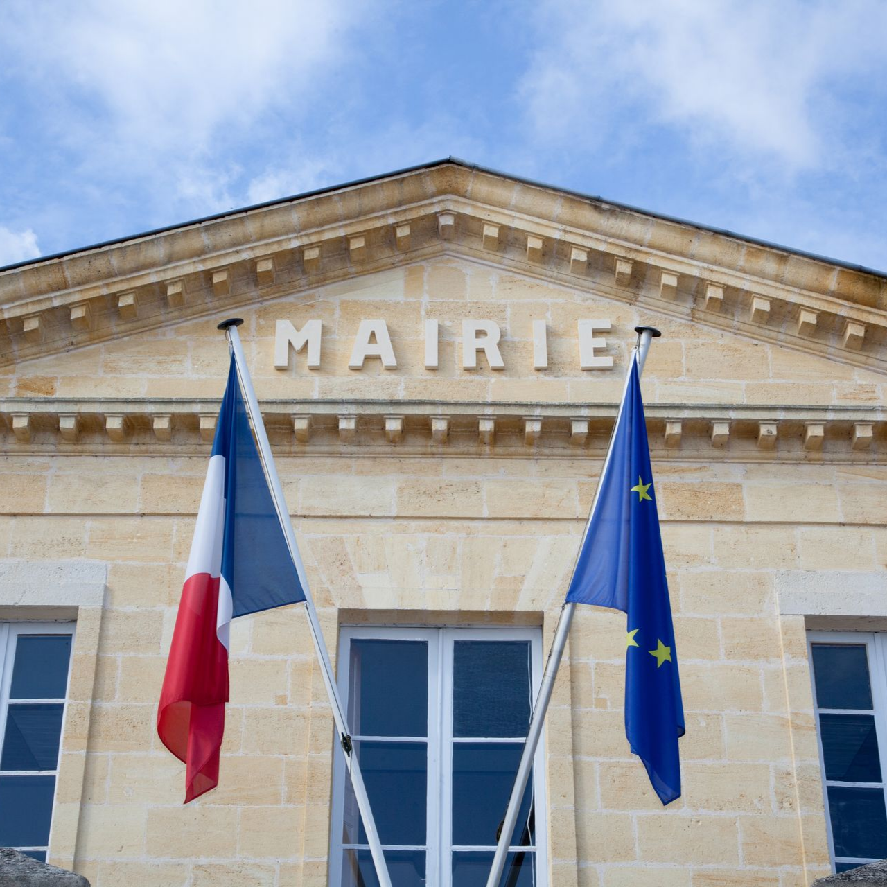 Une mairie avec des drapeaux français et européens flottant.