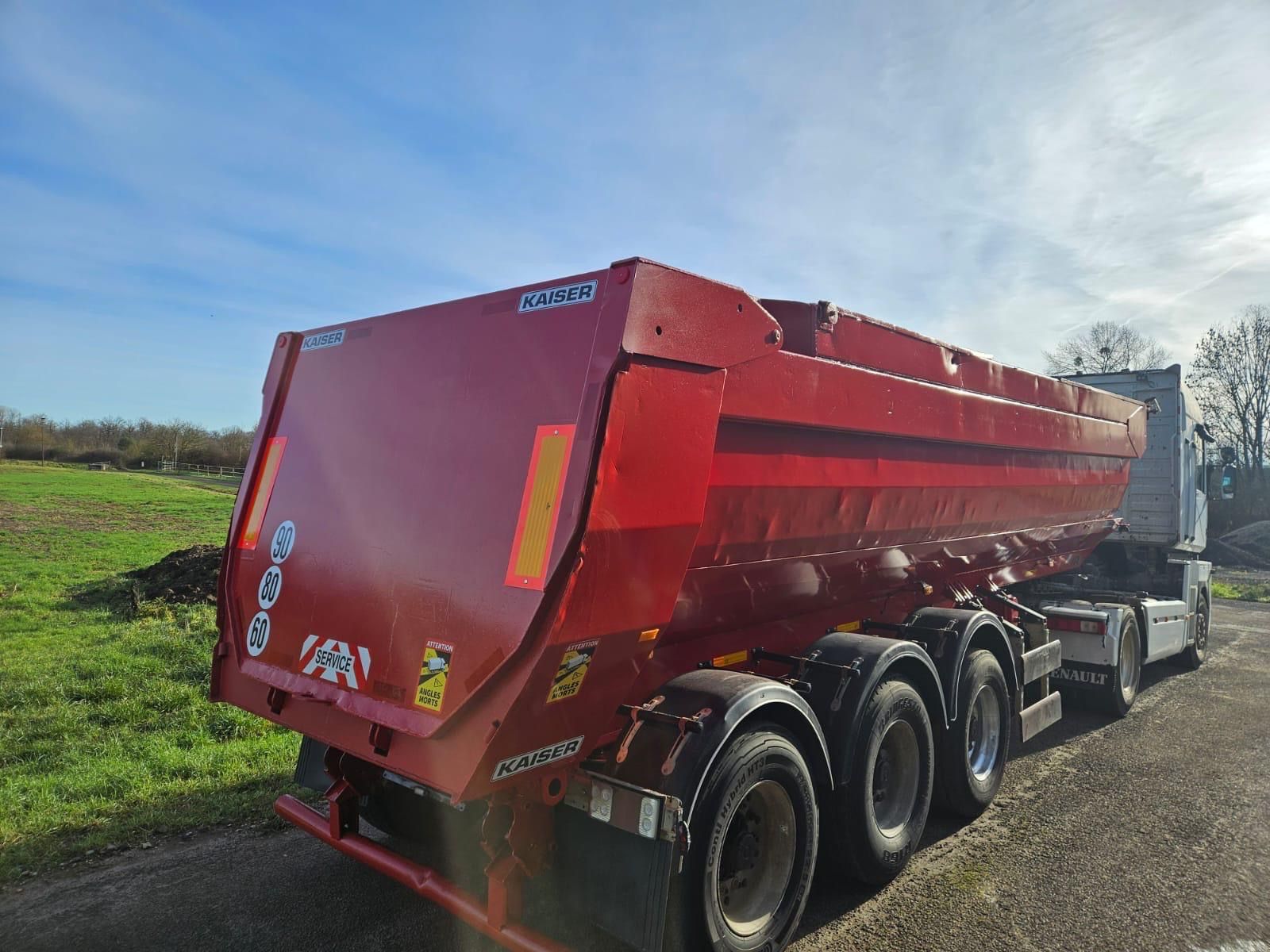 Camion-benne rouge sur le bord d'une route de campagne sous un ciel nuageux