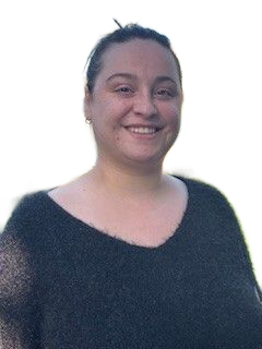 Femme aux longs cheveux bruns, souriante, les bras croisés, portant un pull blanc.