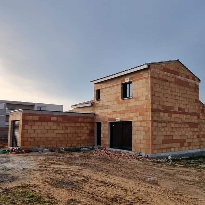Maison en briques inachevée en construction sur un terrain vague au coucher du soleil