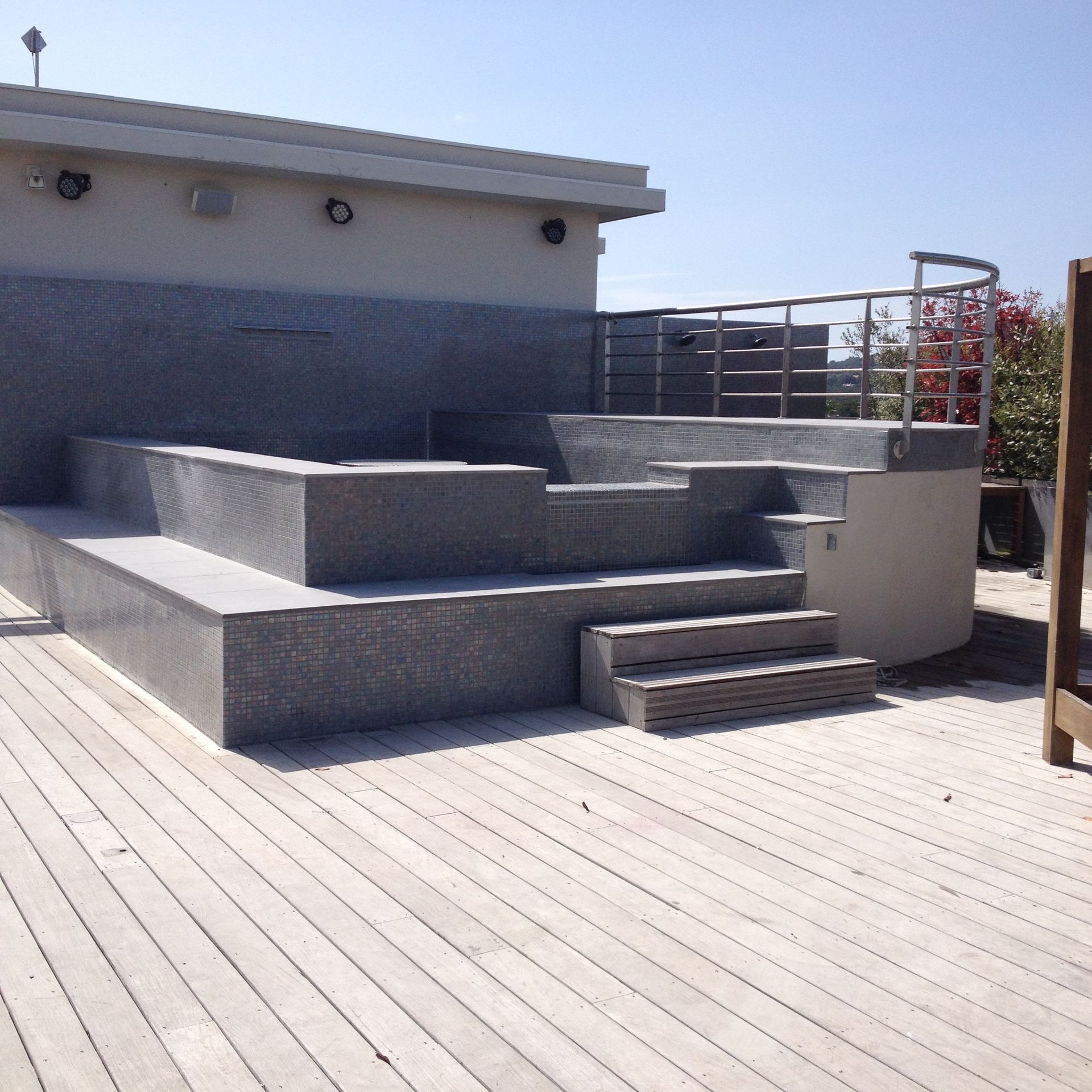 Terrasse extérieure sur le toit avec gradins en béton gris, marches et rambarde sous un ciel lumineux