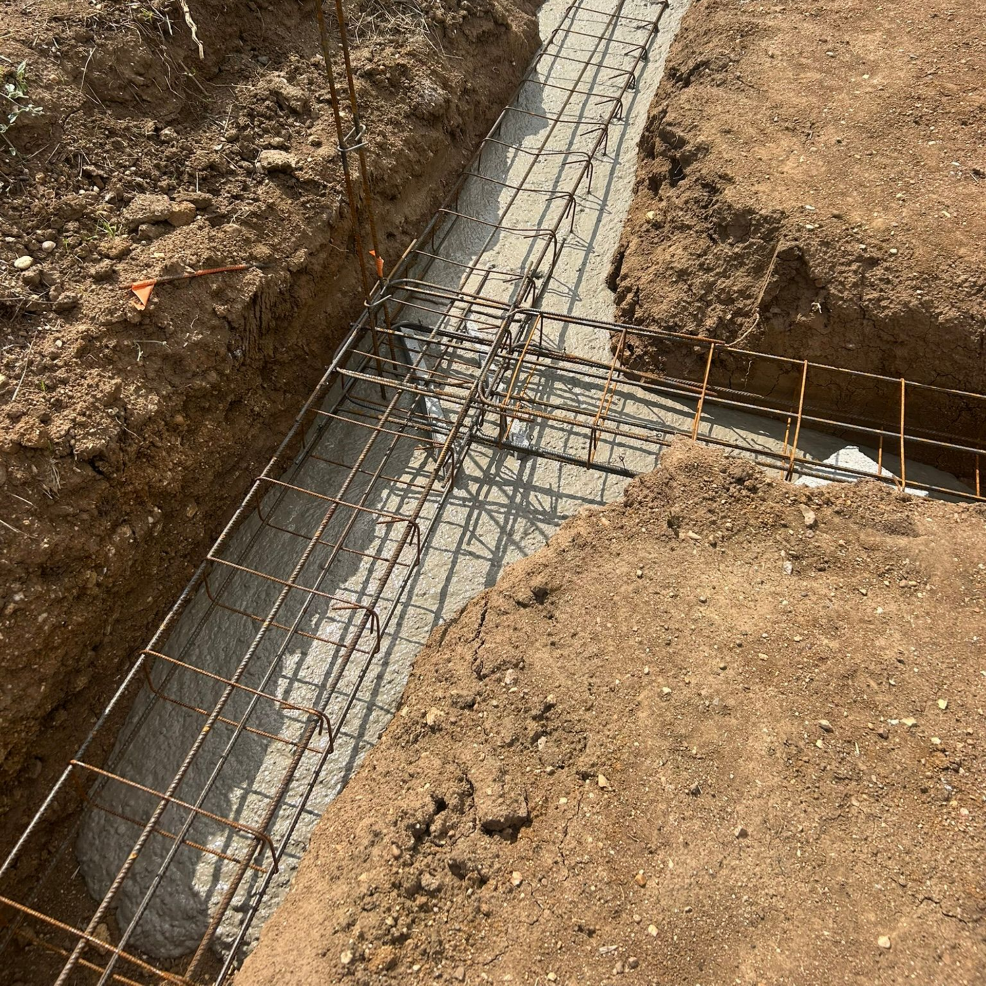 Des barres d'armature en acier ont été posées dans une tranchée de terre en vue du coulage d'une fondation en béton.
