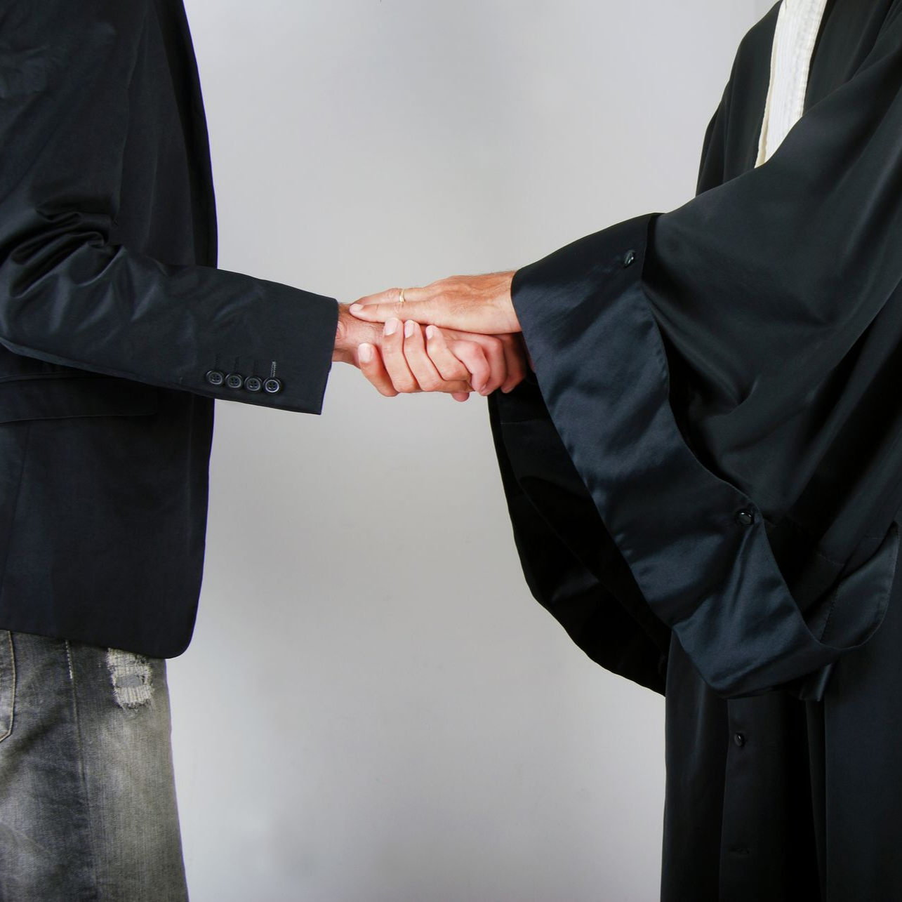 Deux personnes en costume sombre se serrent la main.