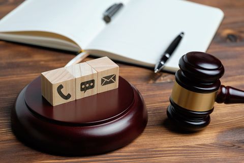 Marteau de cour à côté d'un paquet sur un bureau en bois, avec un carnet ouvert et un stylo.
