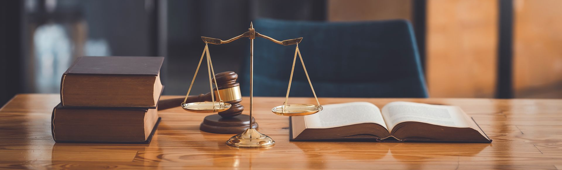 Des ouvrages juridiques, une balance et un livre ouvert sur un bureau en bois.