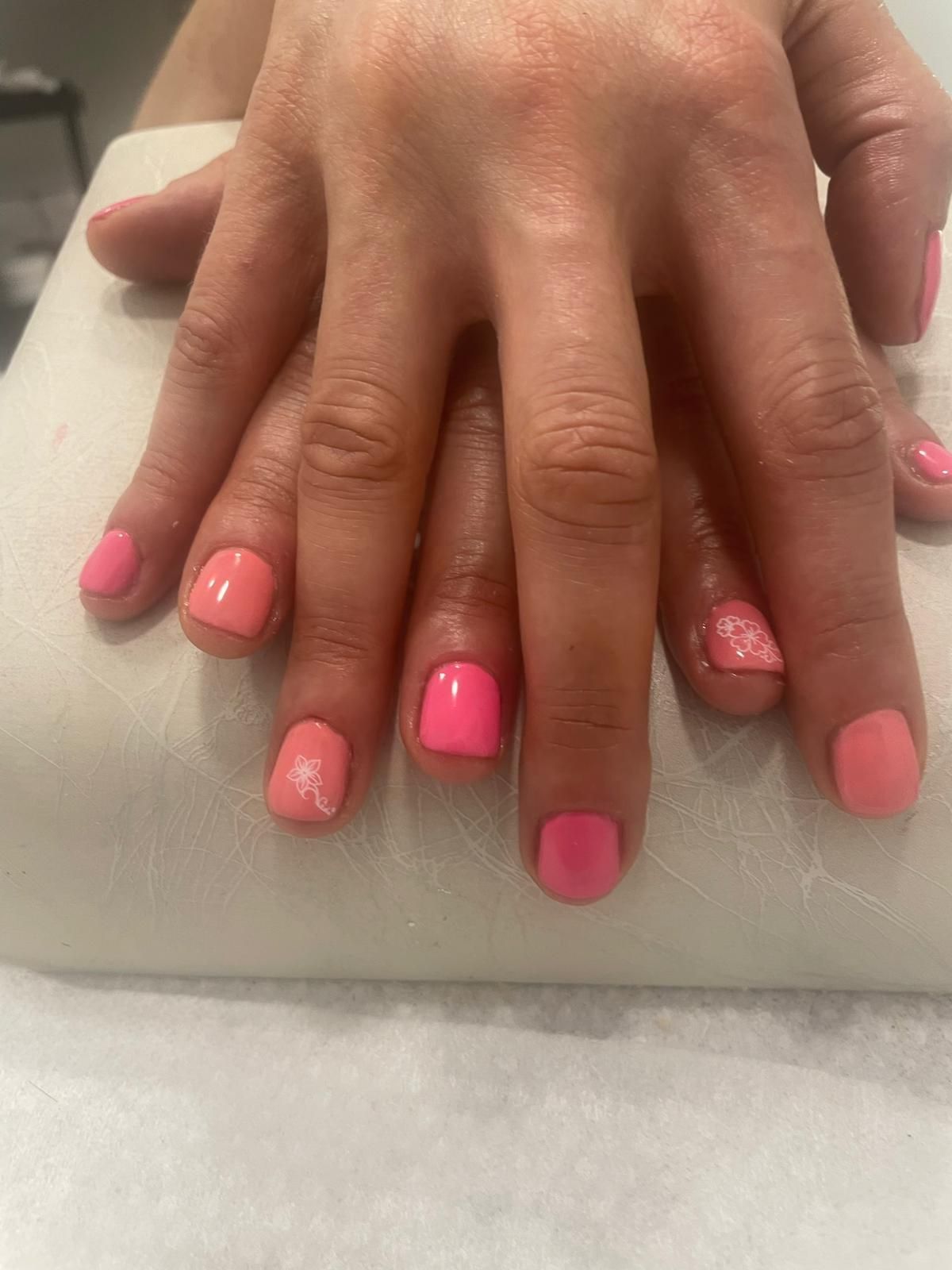 Un primer plano de las manos de una persona con uñas rosadas.