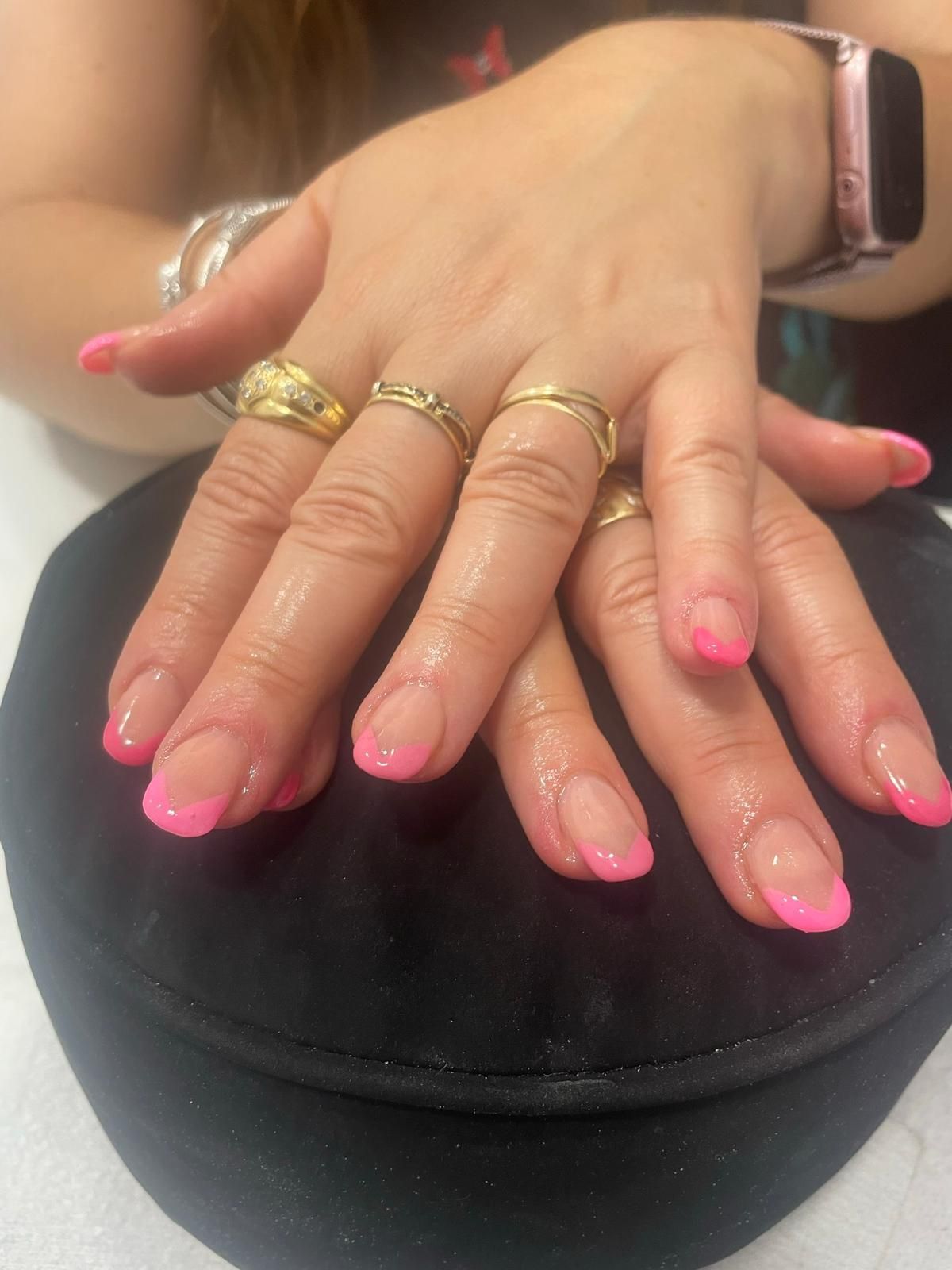 Un primer plano de las manos de una mujer con uñas rosas y anillos.