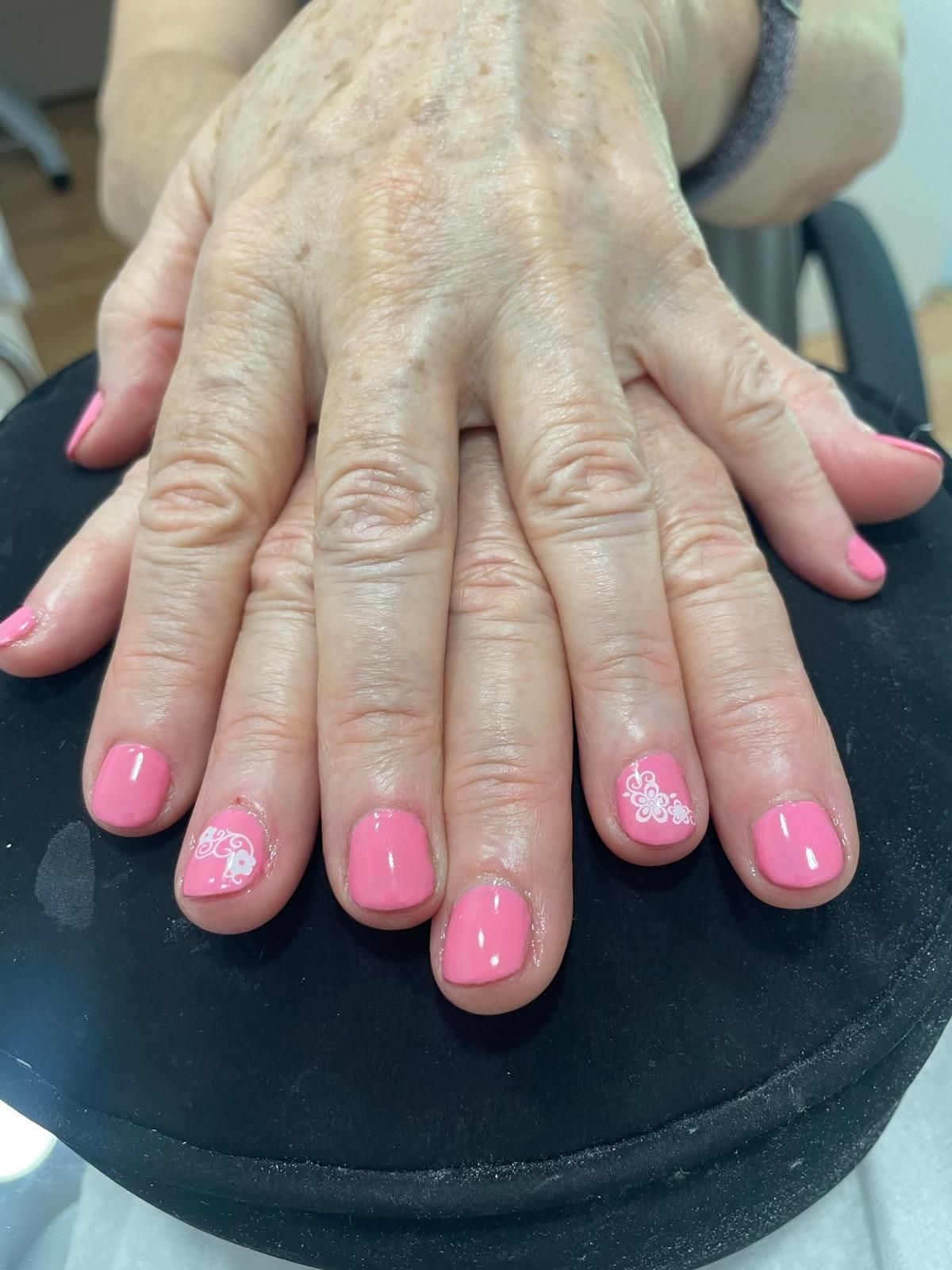 Un primer plano de las manos de una mujer con uñas rosas.