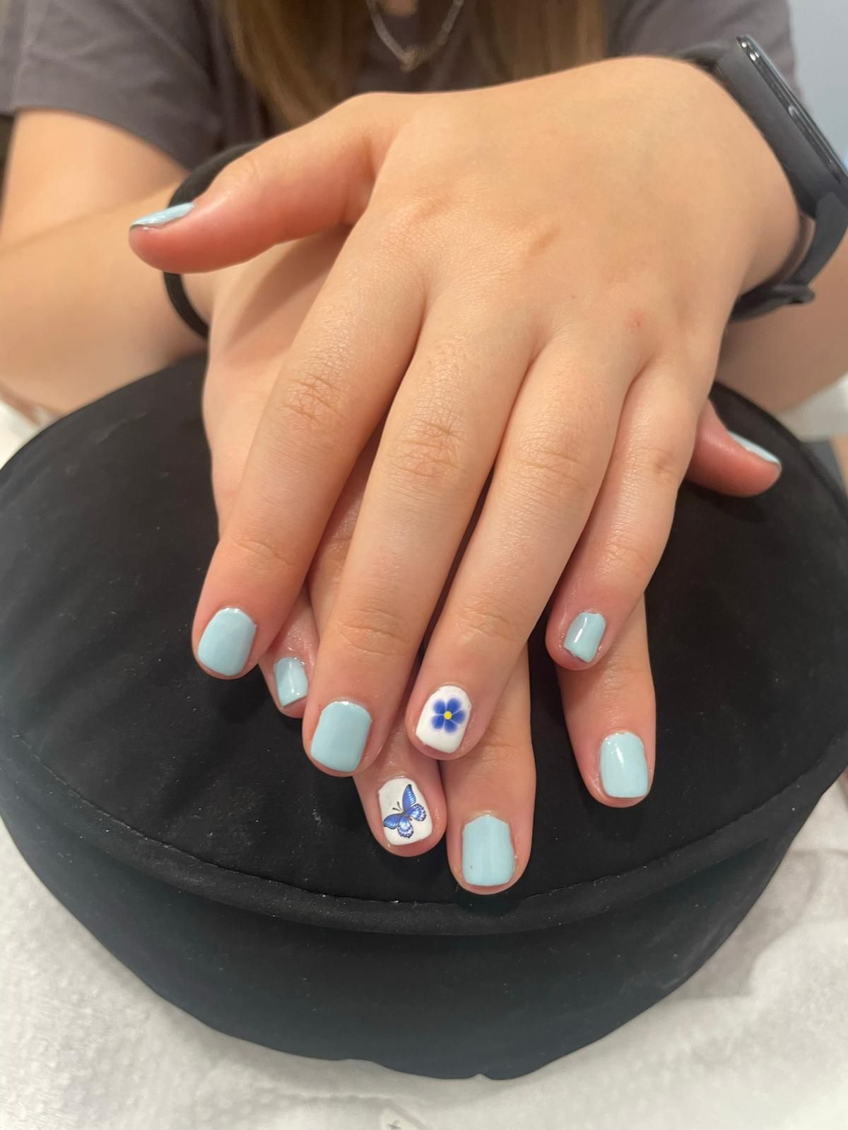 Un primer plano de la mano de una persona con uñas azules y blancas.