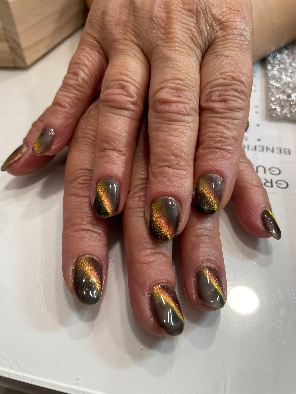 Un primer plano de las uñas de una mujer con un diseño de ojo de gato.