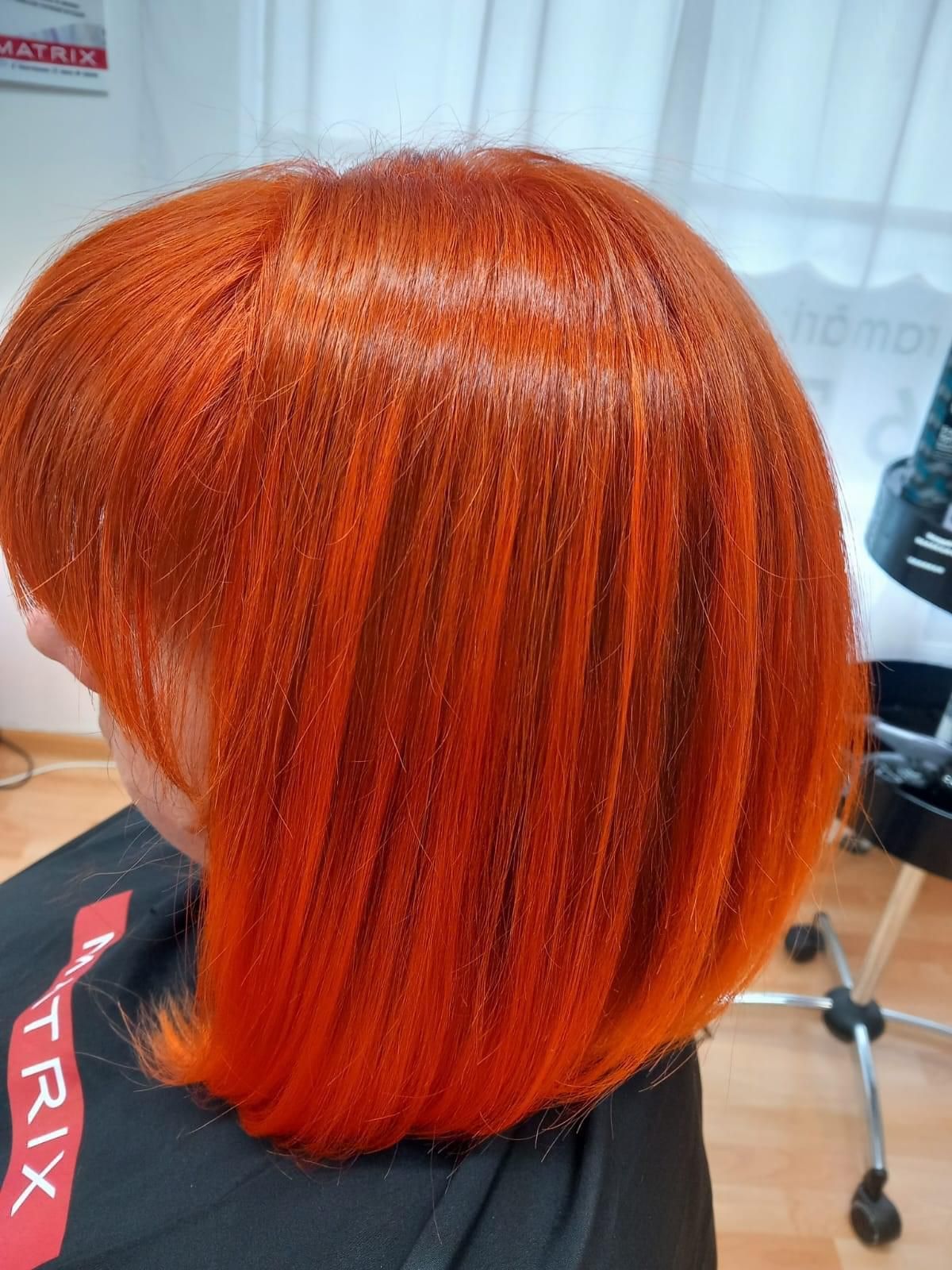 Una mujer con cabello rojo está sentada en una silla en un salón.