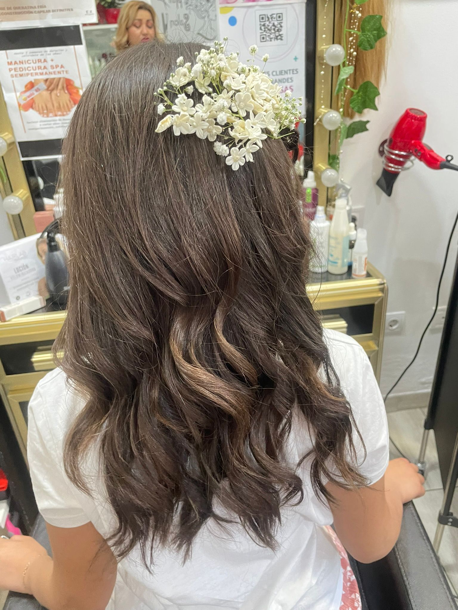 Una mujer se está peinando en un salón con flores en el pelo.
