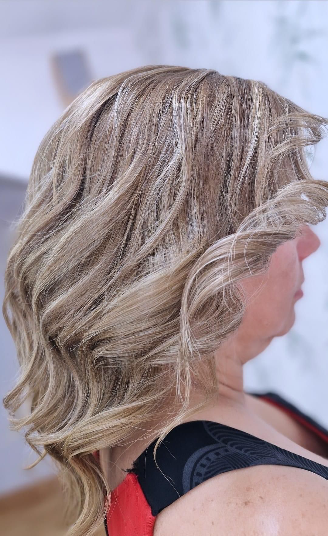 Una mujer con cabello rubio lleva un top rojo y negro.