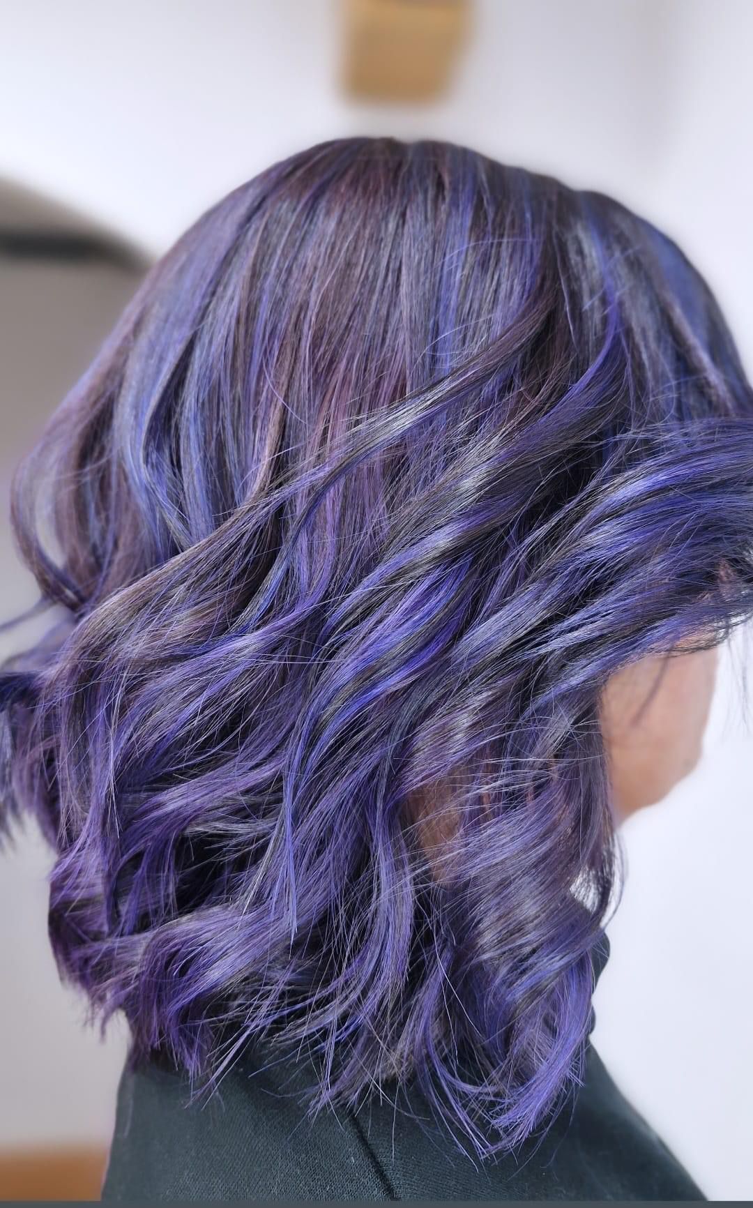 Una mujer con cabello morado está sentada en una silla.