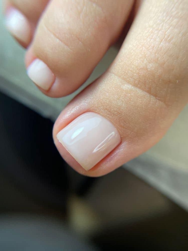 Un primer plano de las uñas de los pies de una persona con esmalte blanco.