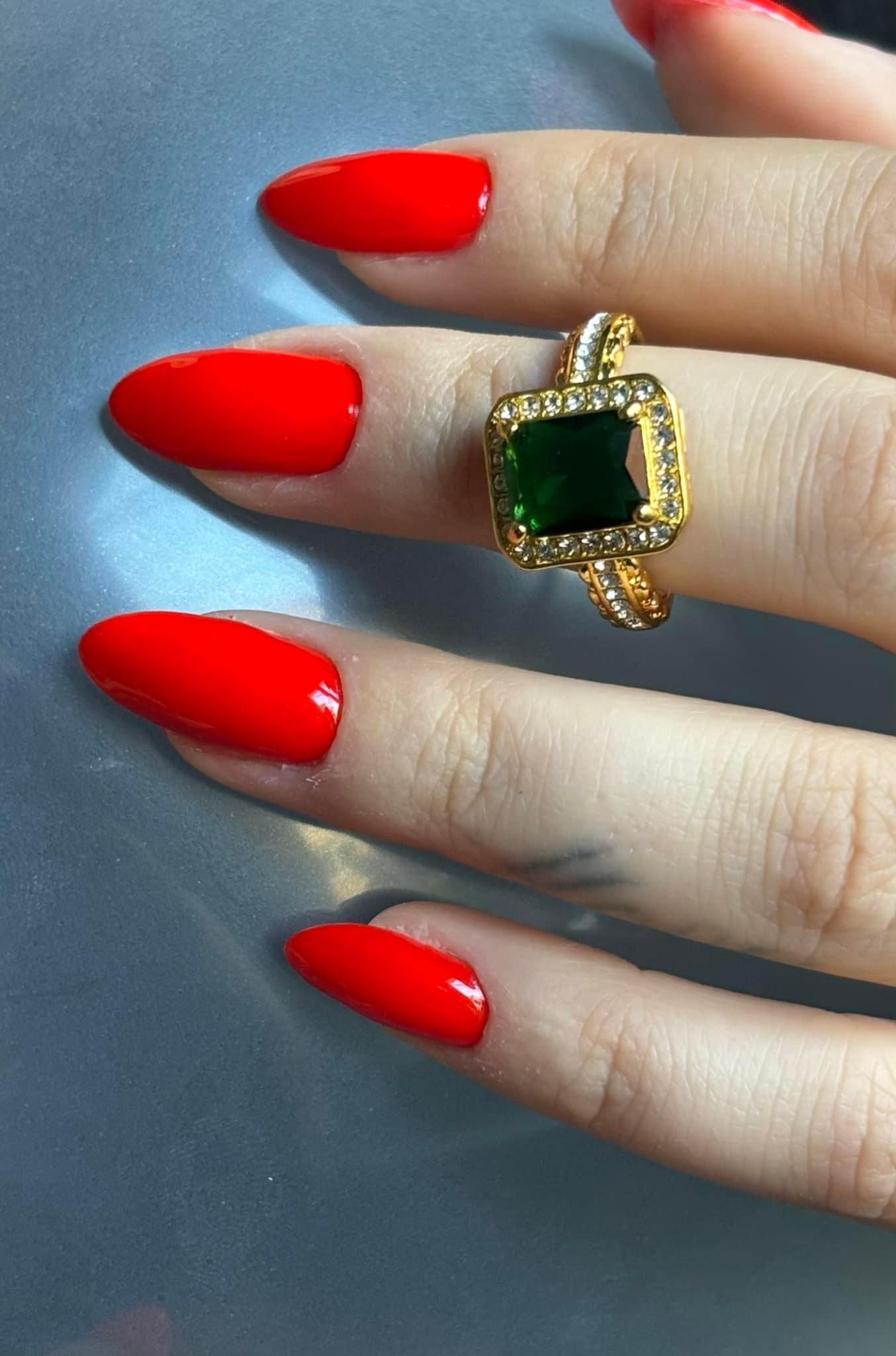 La mano de una mujer con uñas rojas y un anillo en el dedo.