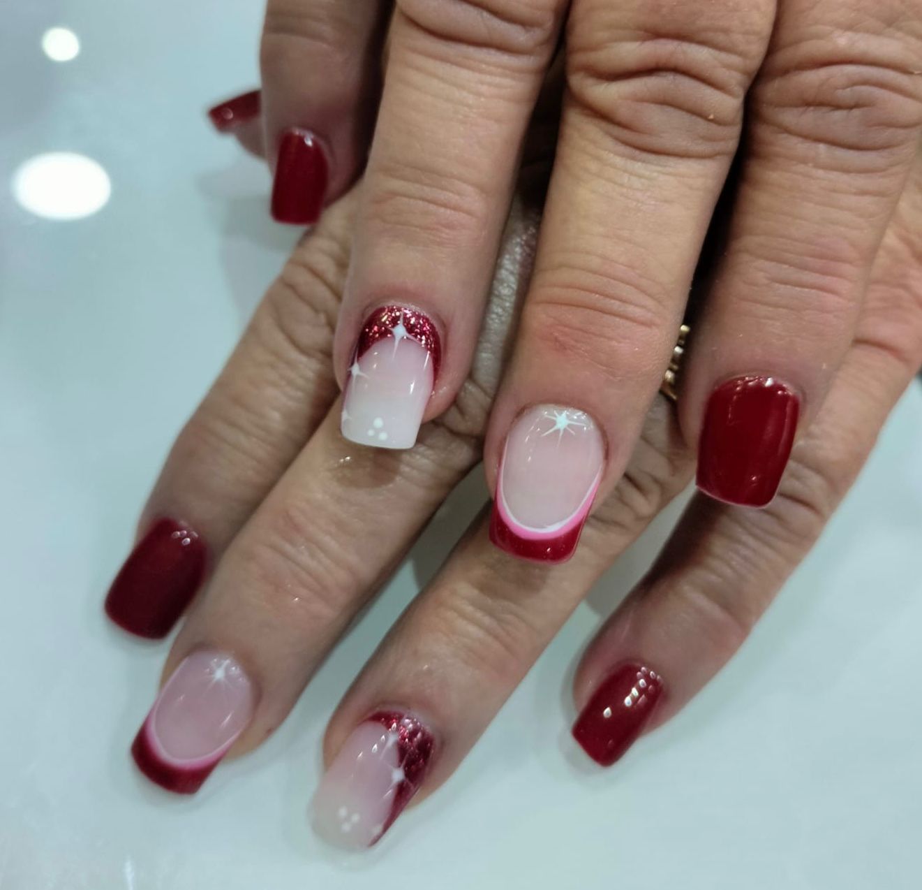 Un primer plano de las manos de una mujer con uñas rojas y blancas.